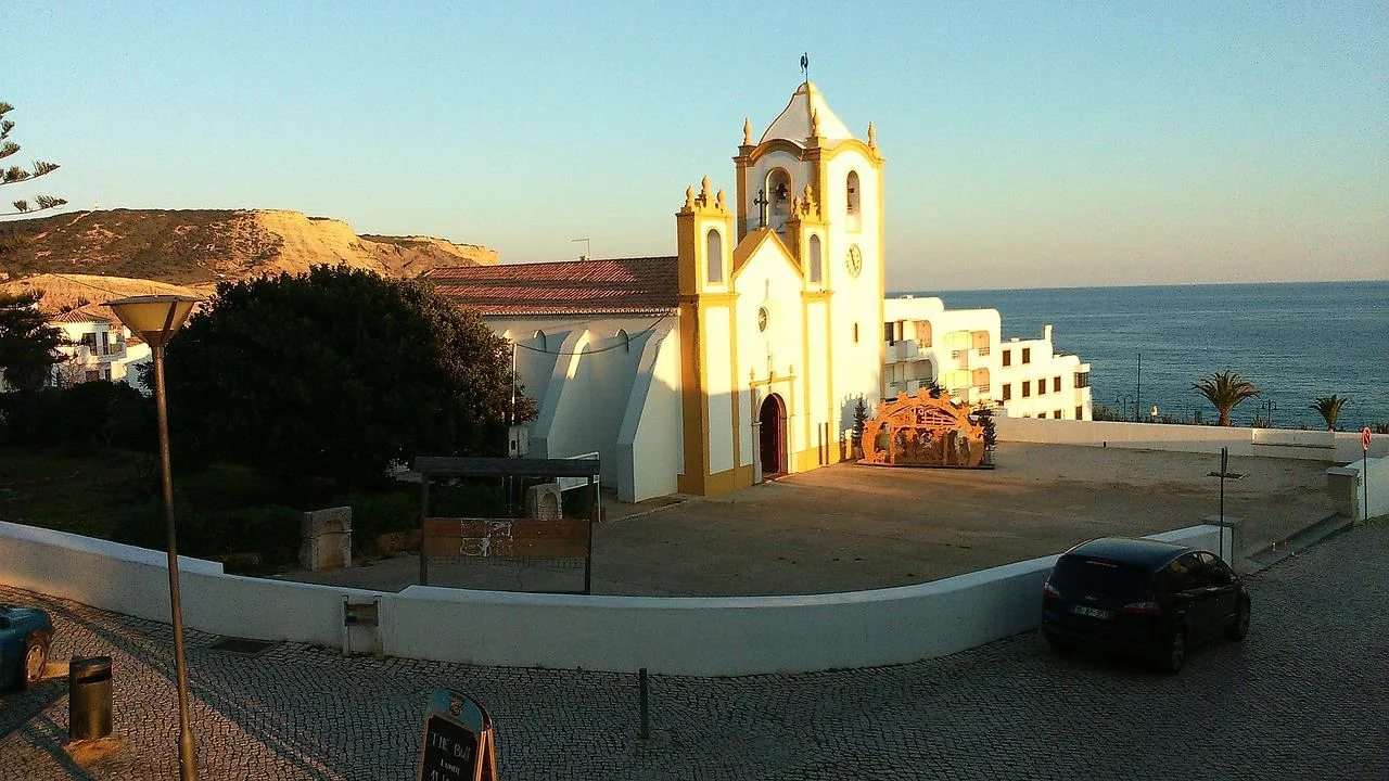 Igreja algarvia de torres brancas e douradas junto ao mar